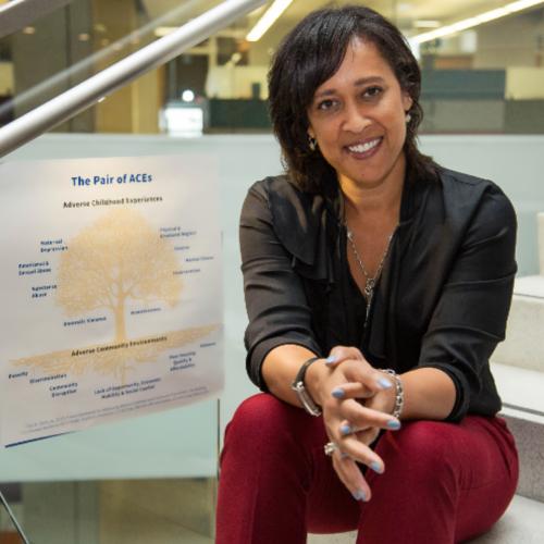 Dr. Wendy Ellis, sitting in front of Pair of Aces Tree poster