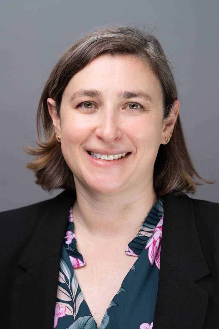 Headshot of Julia Strasser - white woman with shoulder-length light brown hair, a colorful collared shirt and a black blazer