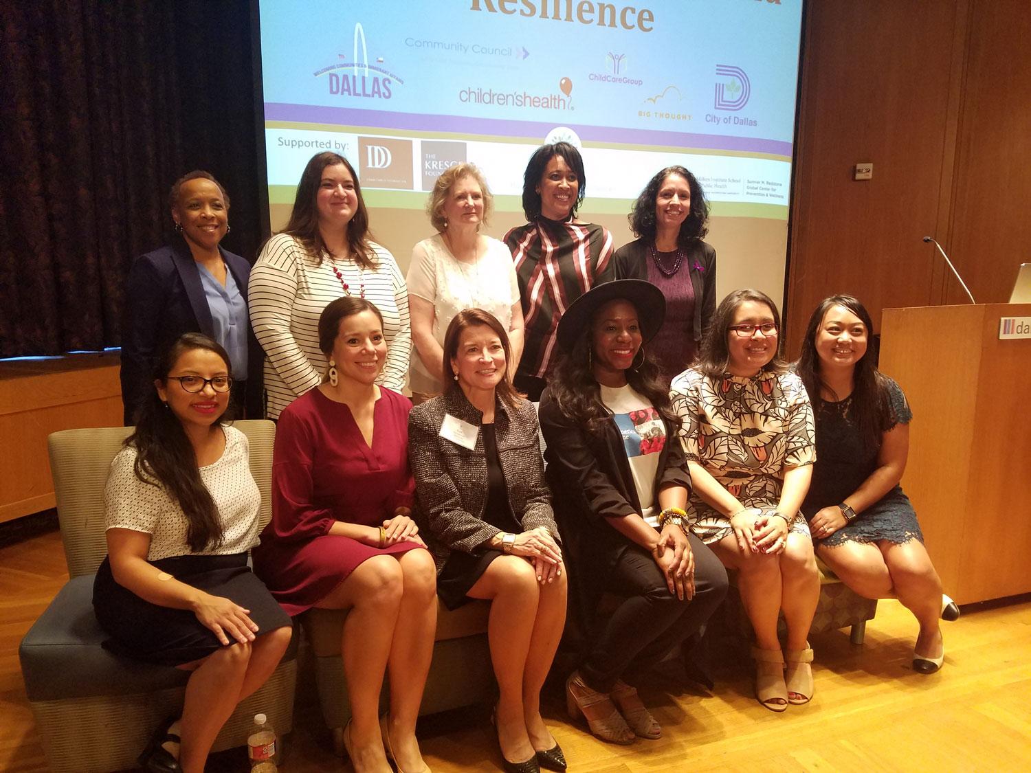 Ten diverse people pose in two rows for picture, in front of screen 